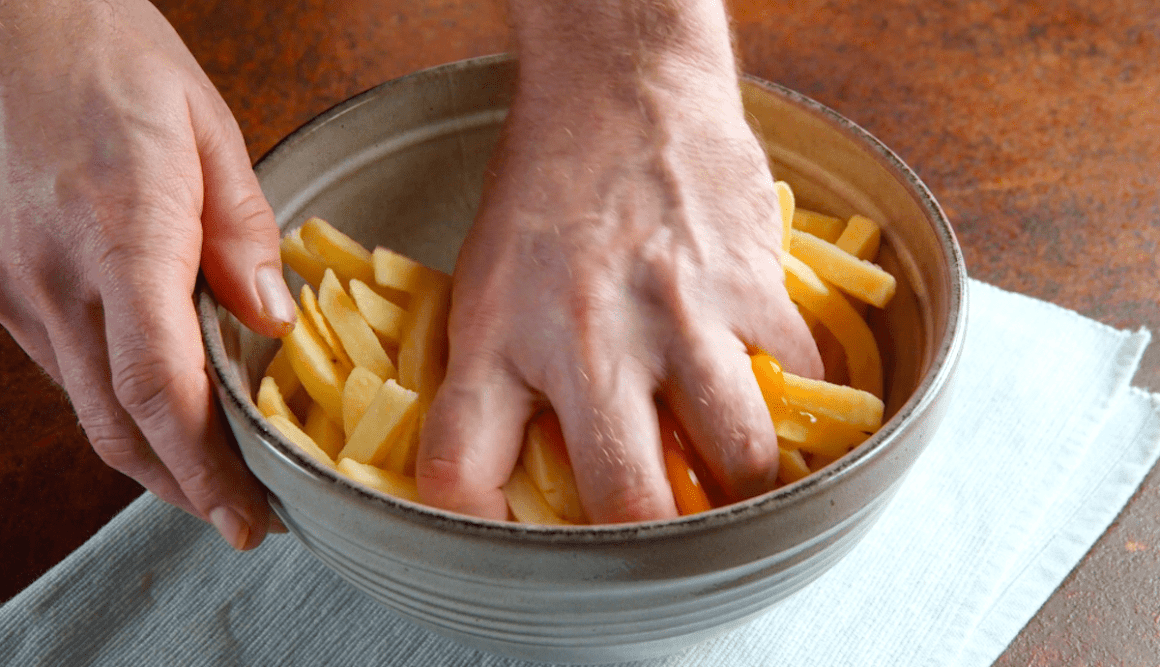 Pommes und ein Ei werden mit den Händen zermatscht