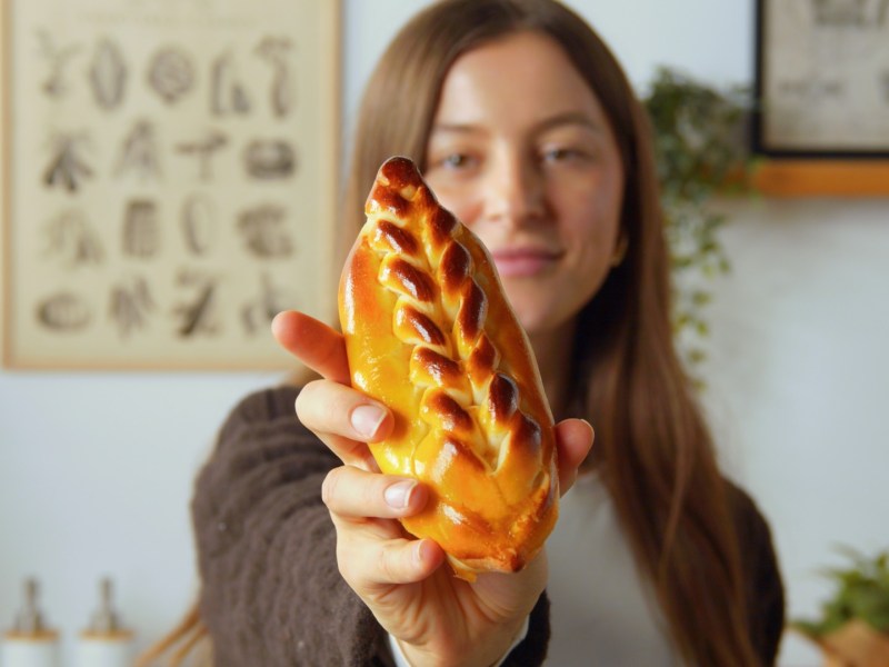 Una cocinera sostiene un panecillo brioche relleno frente a la cámara.