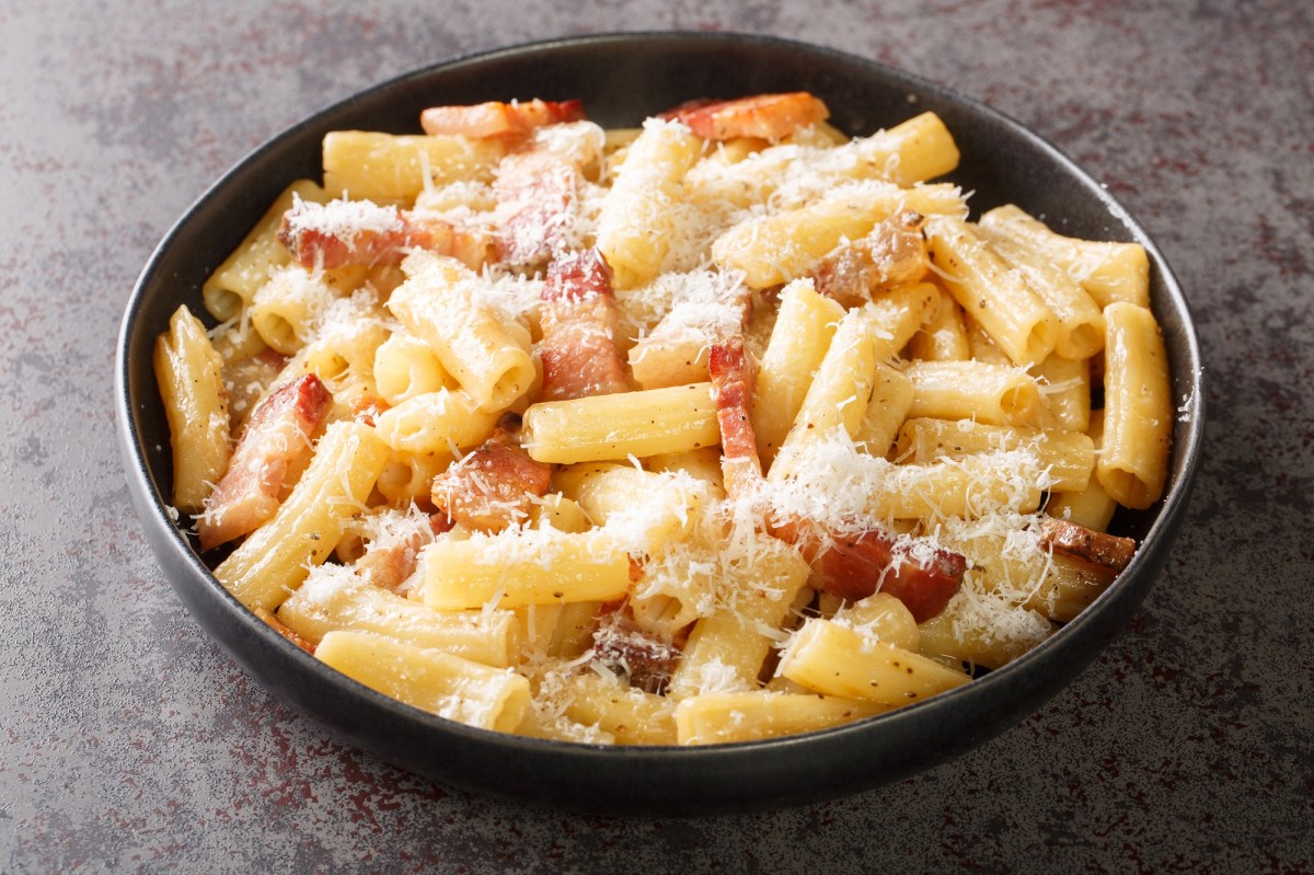 Un plato de pasta a la gricia sobre un fondo oscuro.