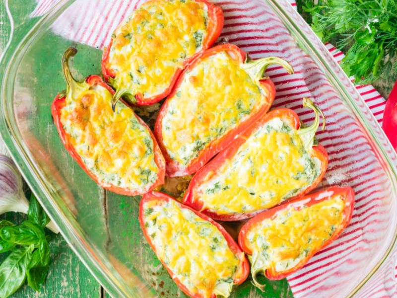 Pimientos rellenos con queso feta y arroz en una fuente transparente para horno. Vista desde arriba.
