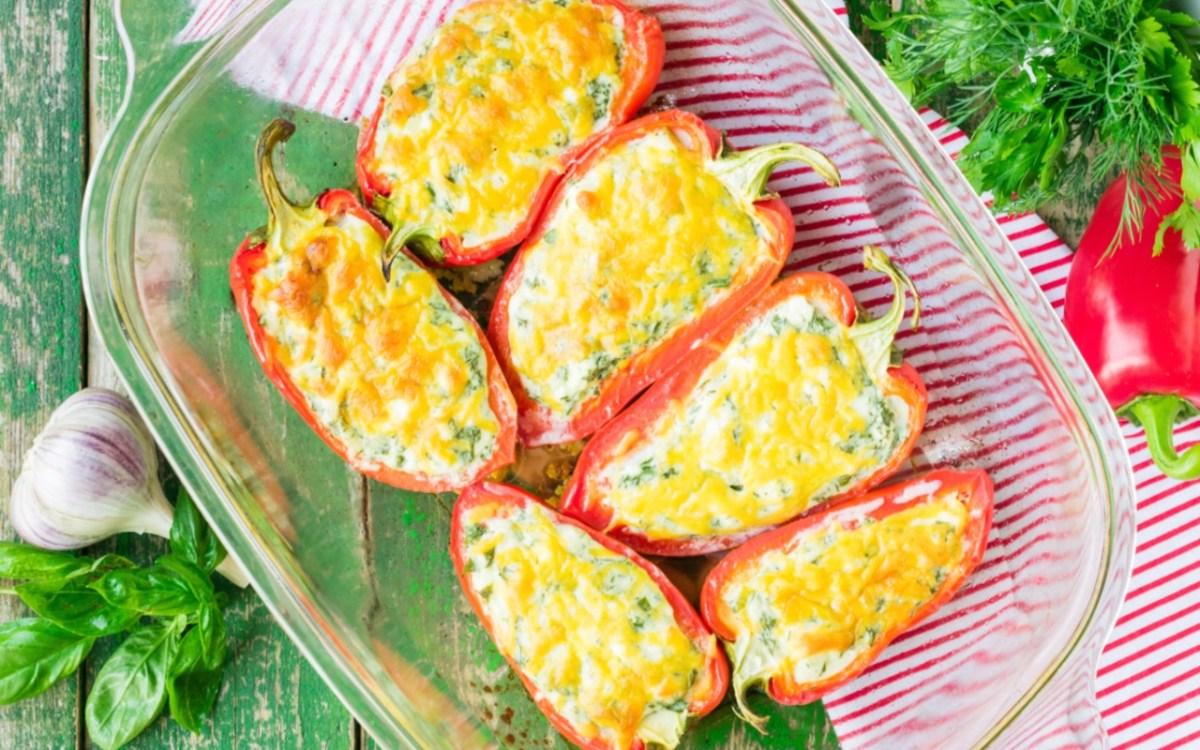 Pimientos rellenos con queso feta y arroz en una fuente transparente para horno. Vista desde arriba.
