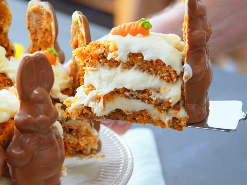 Un cocinero toma un trozo de tarta de conejito de Pascua con conejitos de chocolate.
