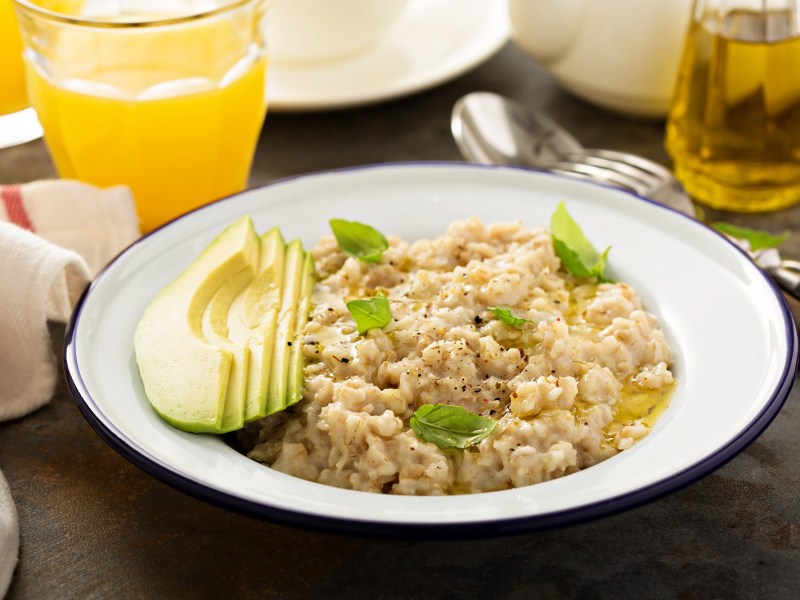 Gachas de avena con aguacate y aceite de oliva en un plato, acompañado de diversas bebidas.