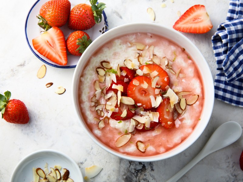 Tazón con gachas de fresa y almendra y fresas al lado