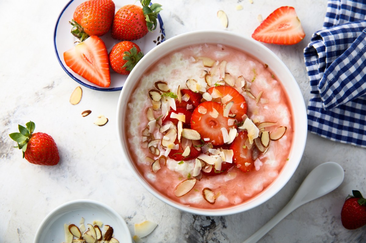 Tazón con gachas de fresa y almendra y fresas al lado