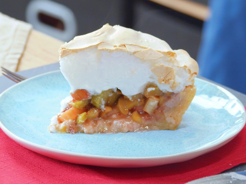 Un trozo de tarta de ruibarbo con merengue en un plato elegante.