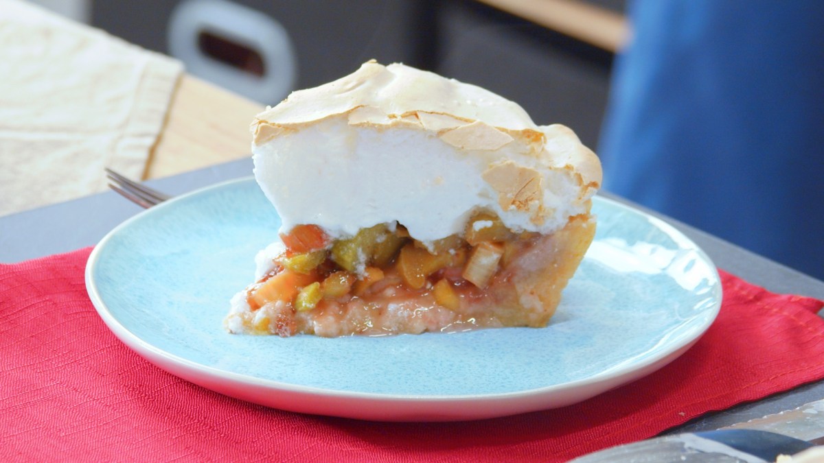 Un trozo de tarta de ruibarbo con merengue en un plato elegante.