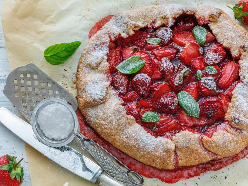 Una galette de fresas decorada con azúcar glas y albahaca.