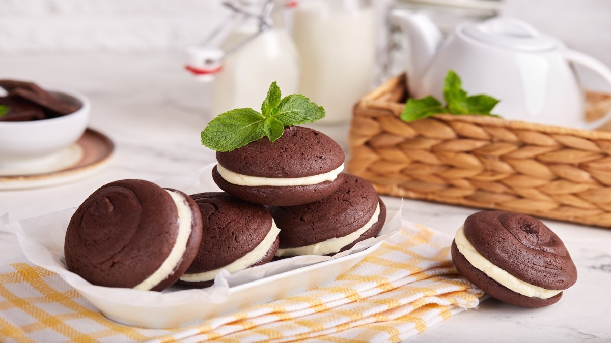 Varias whoopie pies en un plato, rodeadas por piezas de vajilla.