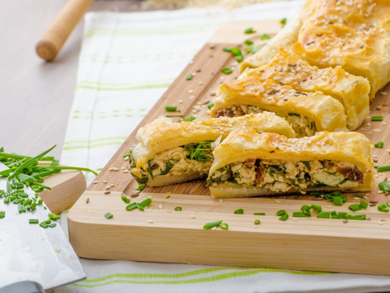 Tabla con strudel de hojaldre con espinacas y queso azul cortado